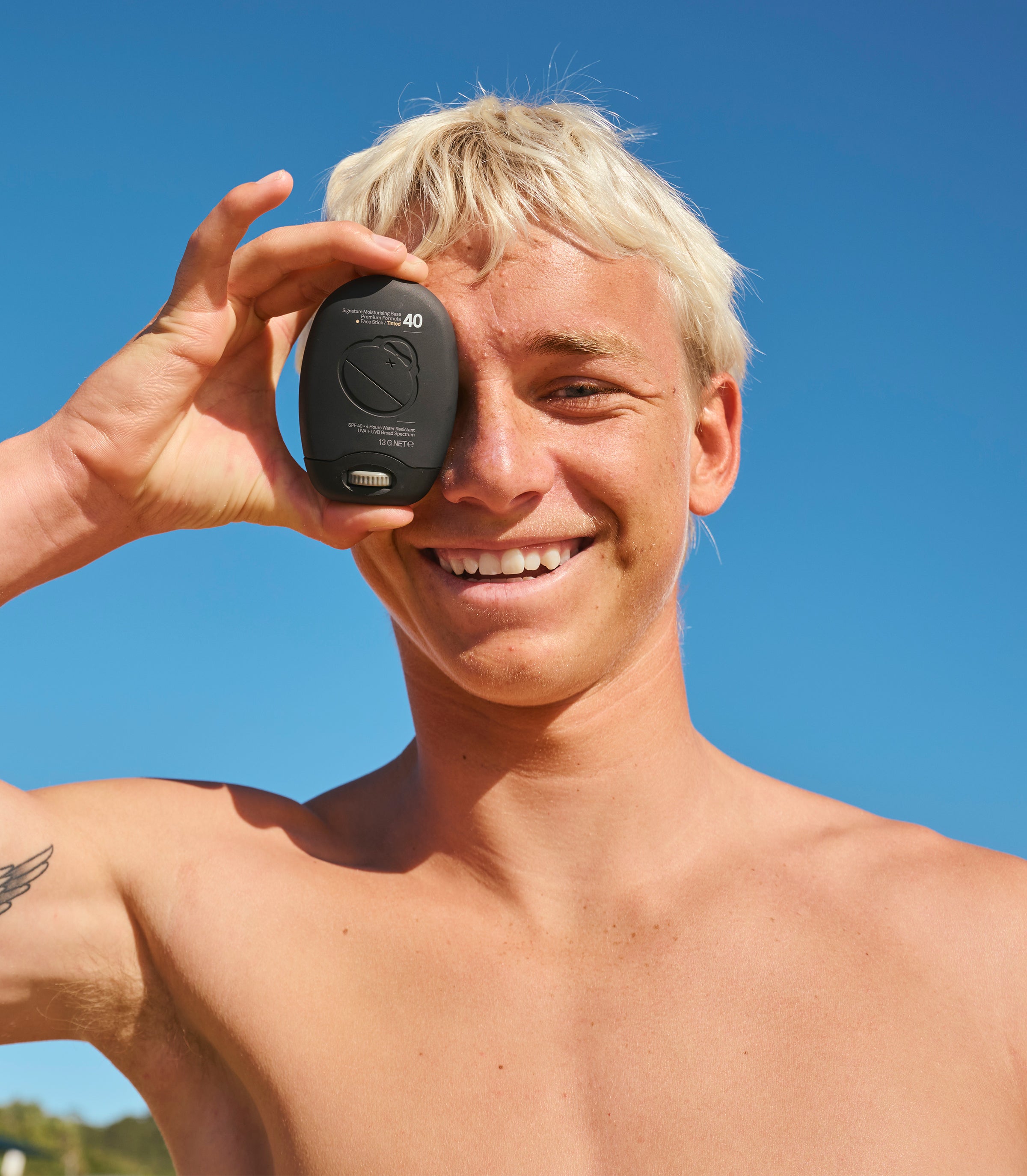 Man holding a black device with a screen against a clear blue sky