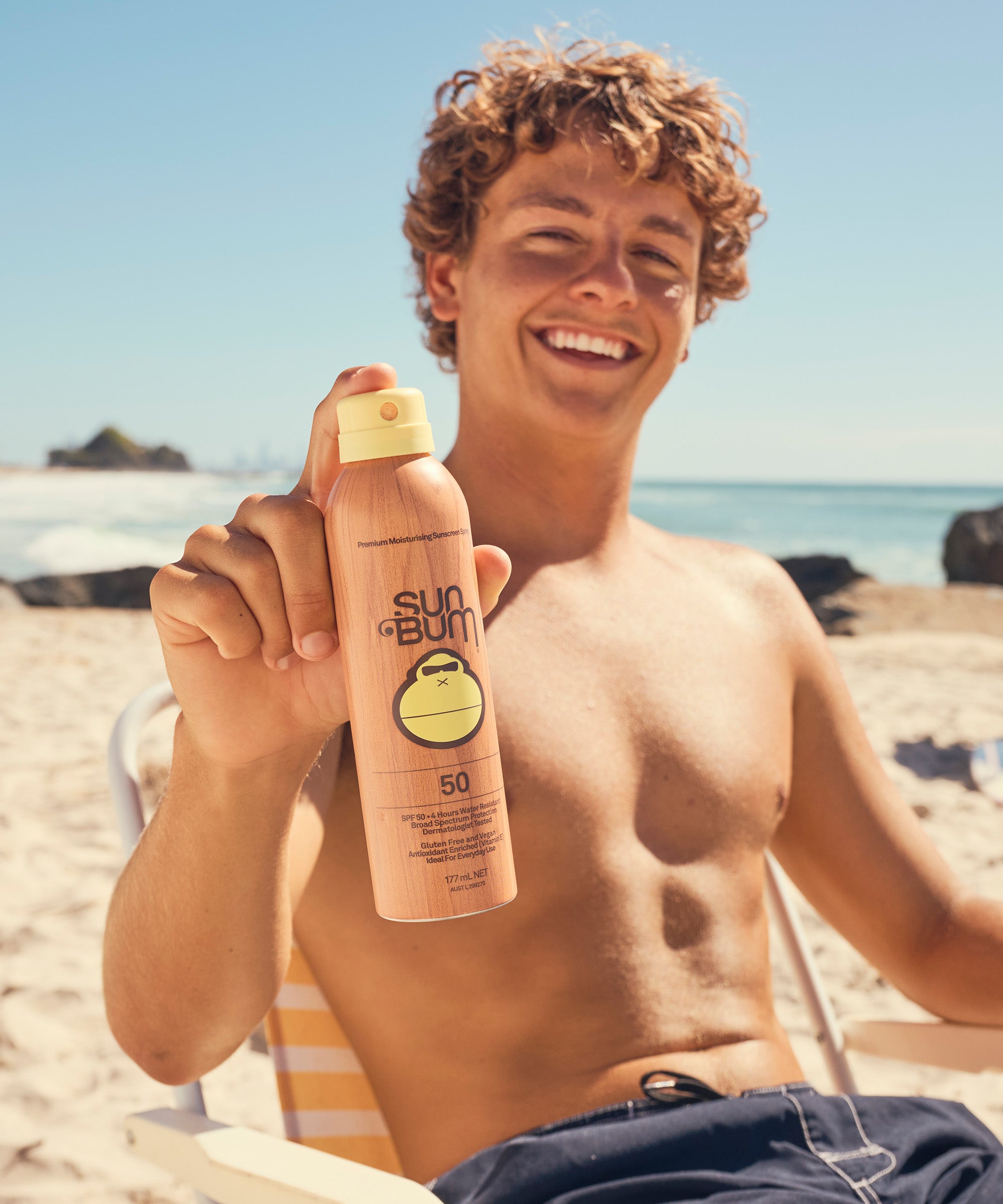 Man on a beach holding a Sun Bum sunscreen bottle