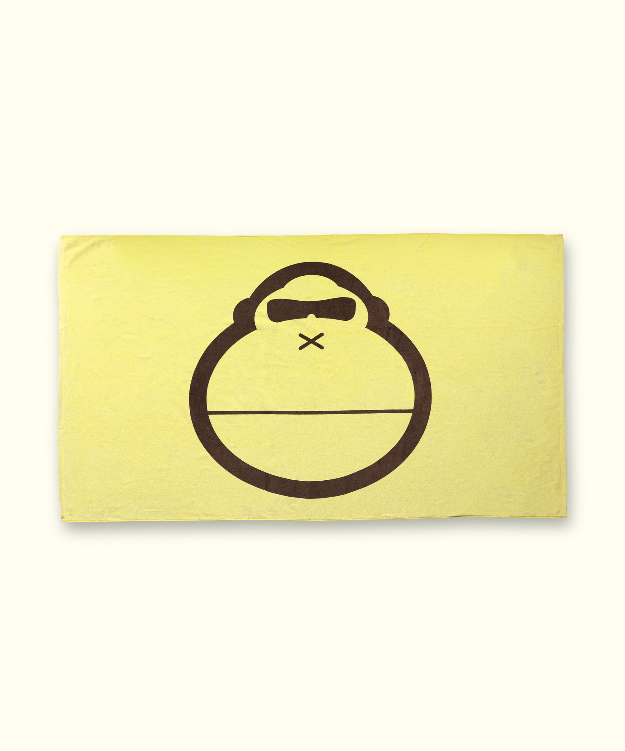 A beach towel with a character's face depicted in the center, predominantly yellow with a brown graphic.