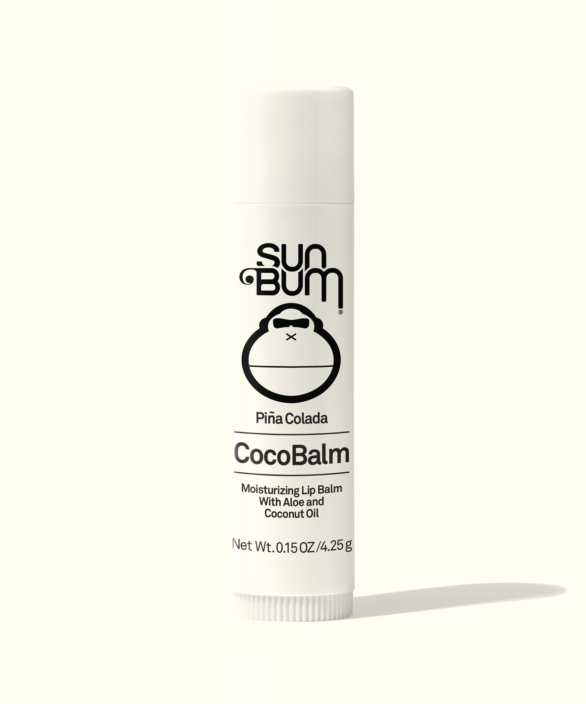 A white twist-up stick of CocoBalm lip balm with black and red text, indicating it is Piña Colada flavored and contains coconut oil.