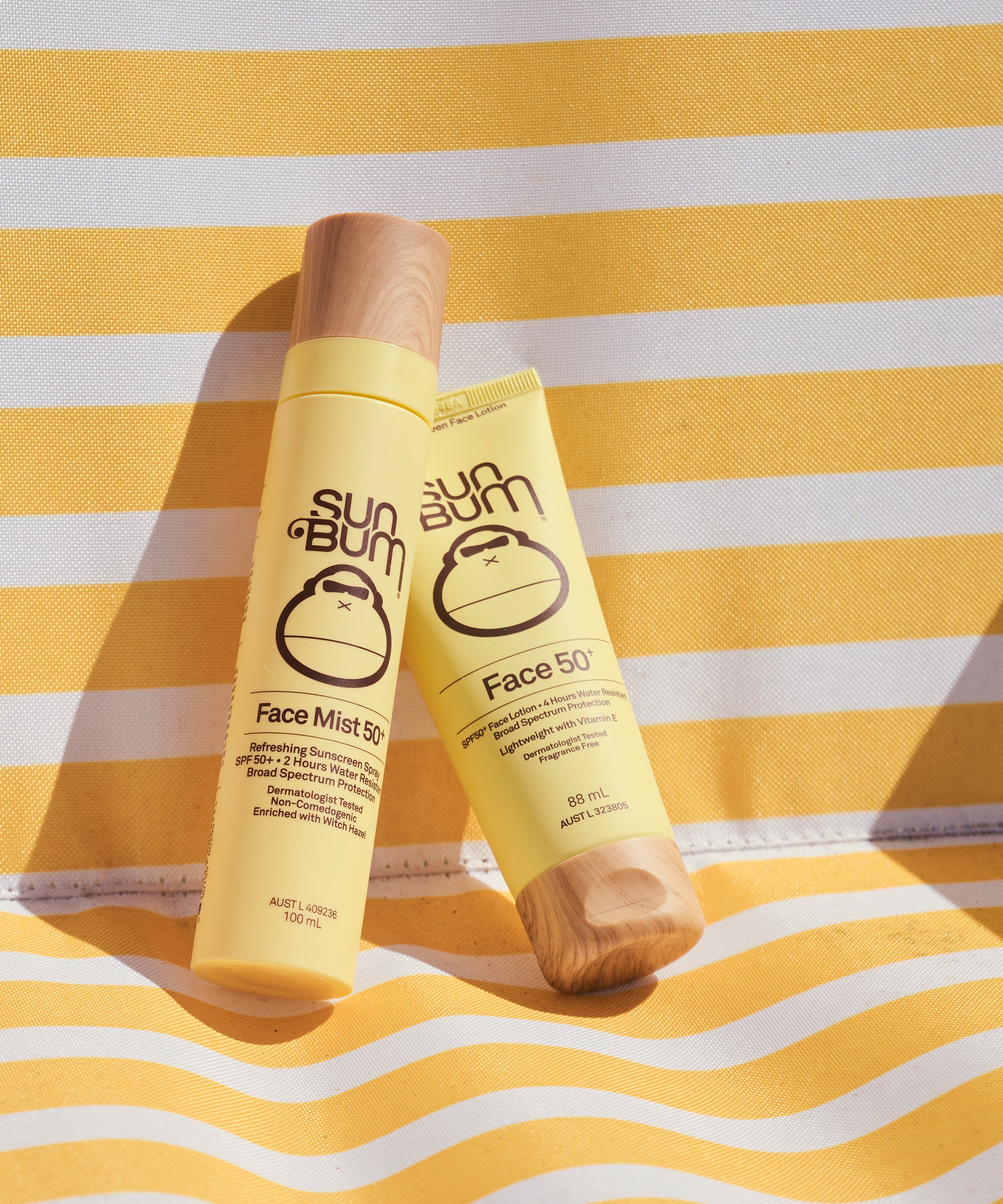 Two bottles of Sun Bum Face Mist SPF 50 on a yellow and white striped background