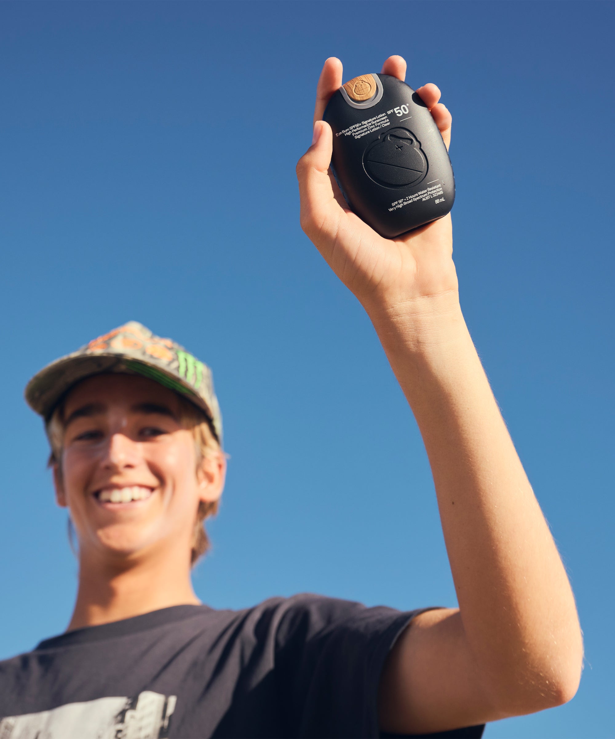 Person holding a black device against a clear blue sky