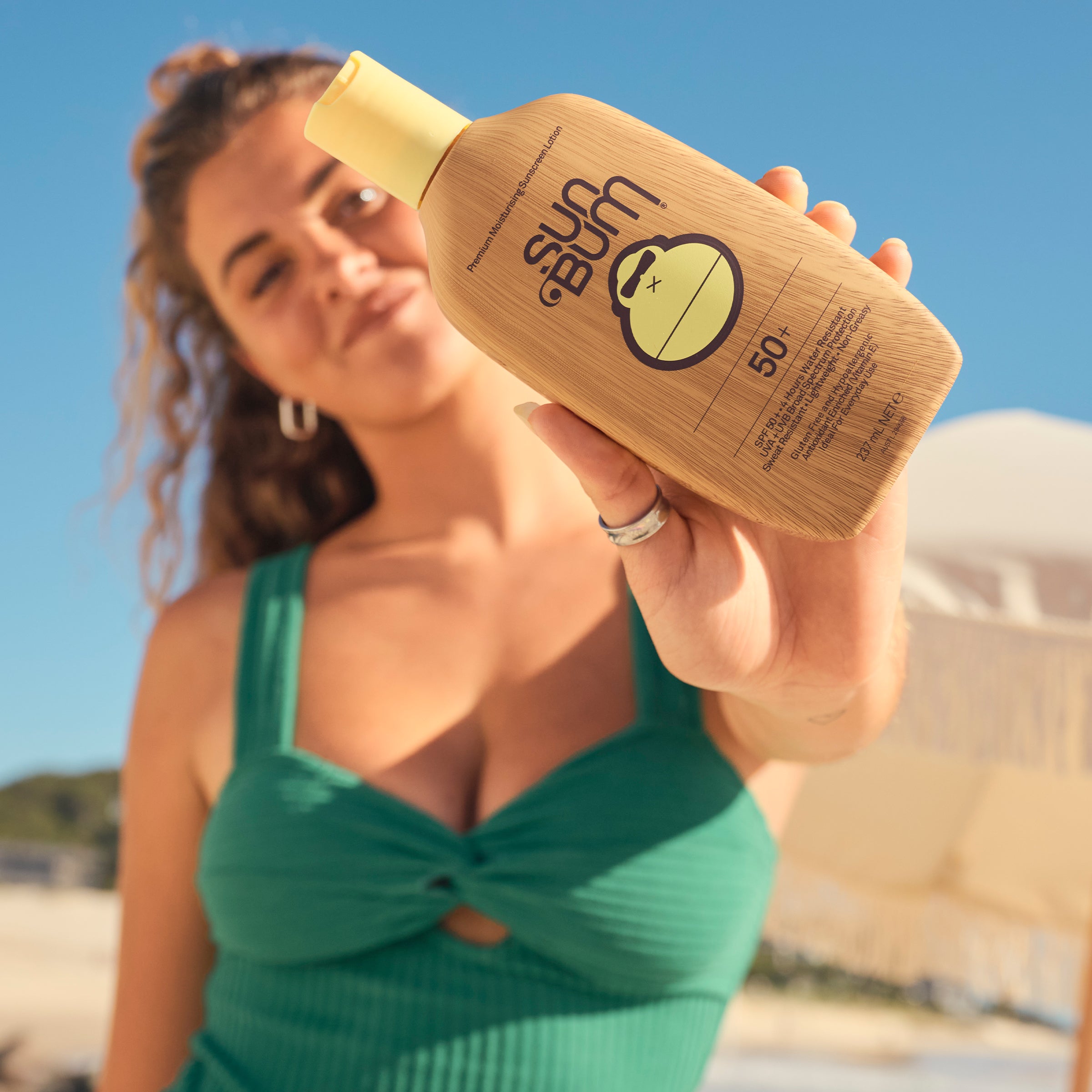 Woman holding a Sun Bum sunscreen bottle on a beach