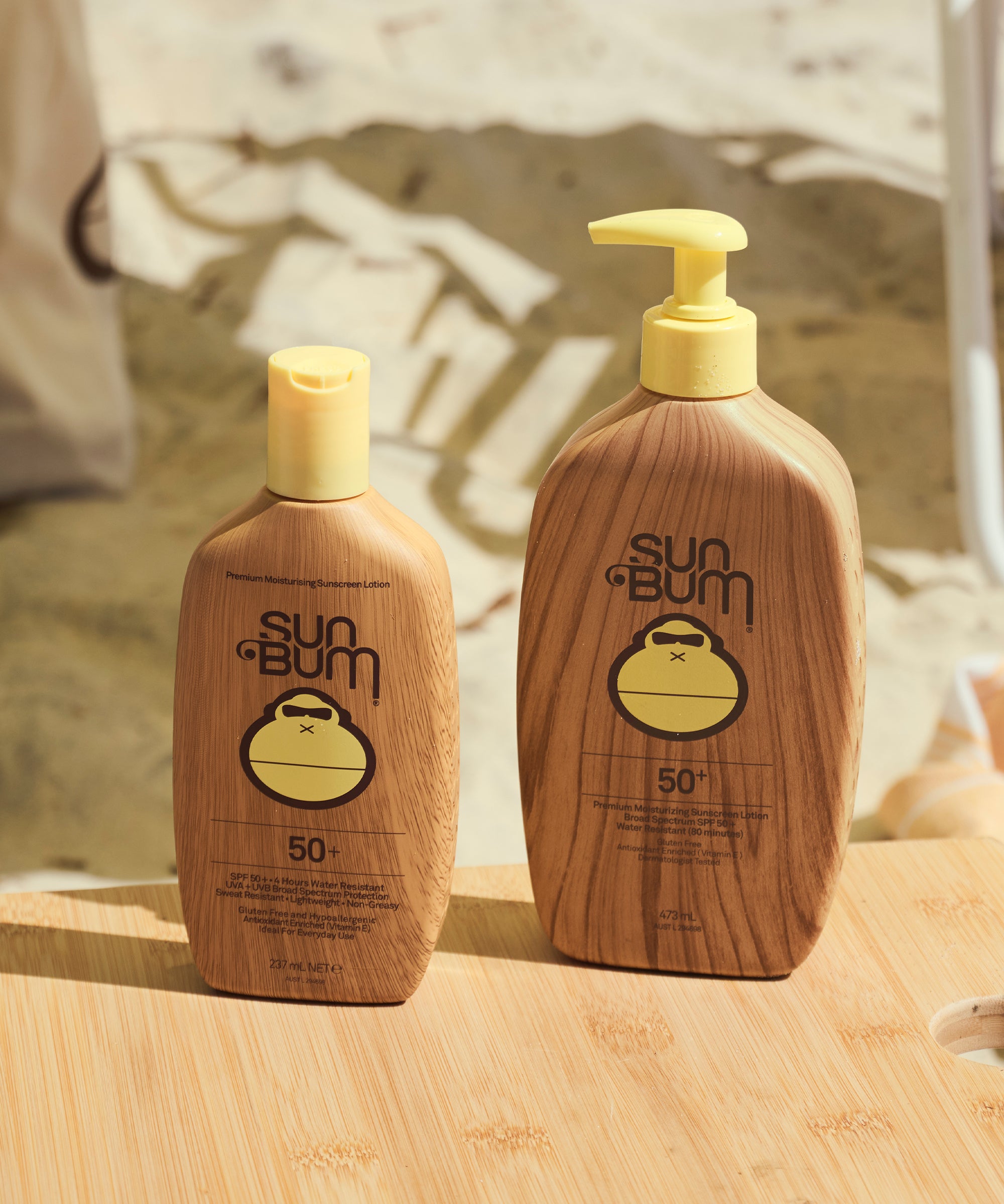 Two Sun Bum bottles on a wooden surface with a beach background