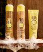 Three yellow Sun Bum hair care products, including shampoo, conditioner, and Revitalizing Hair Mask, displayed on wooden surface with foamy bubbles, showcasing complete hair care system by Sun Bum