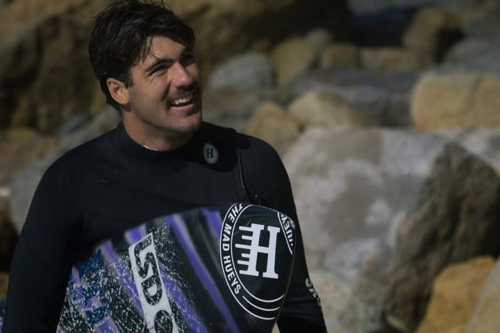 Person wearing a wetsuit with a visible brand logo against a rocky background