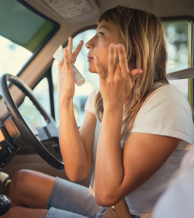 Woman applying sunscreen inside a car