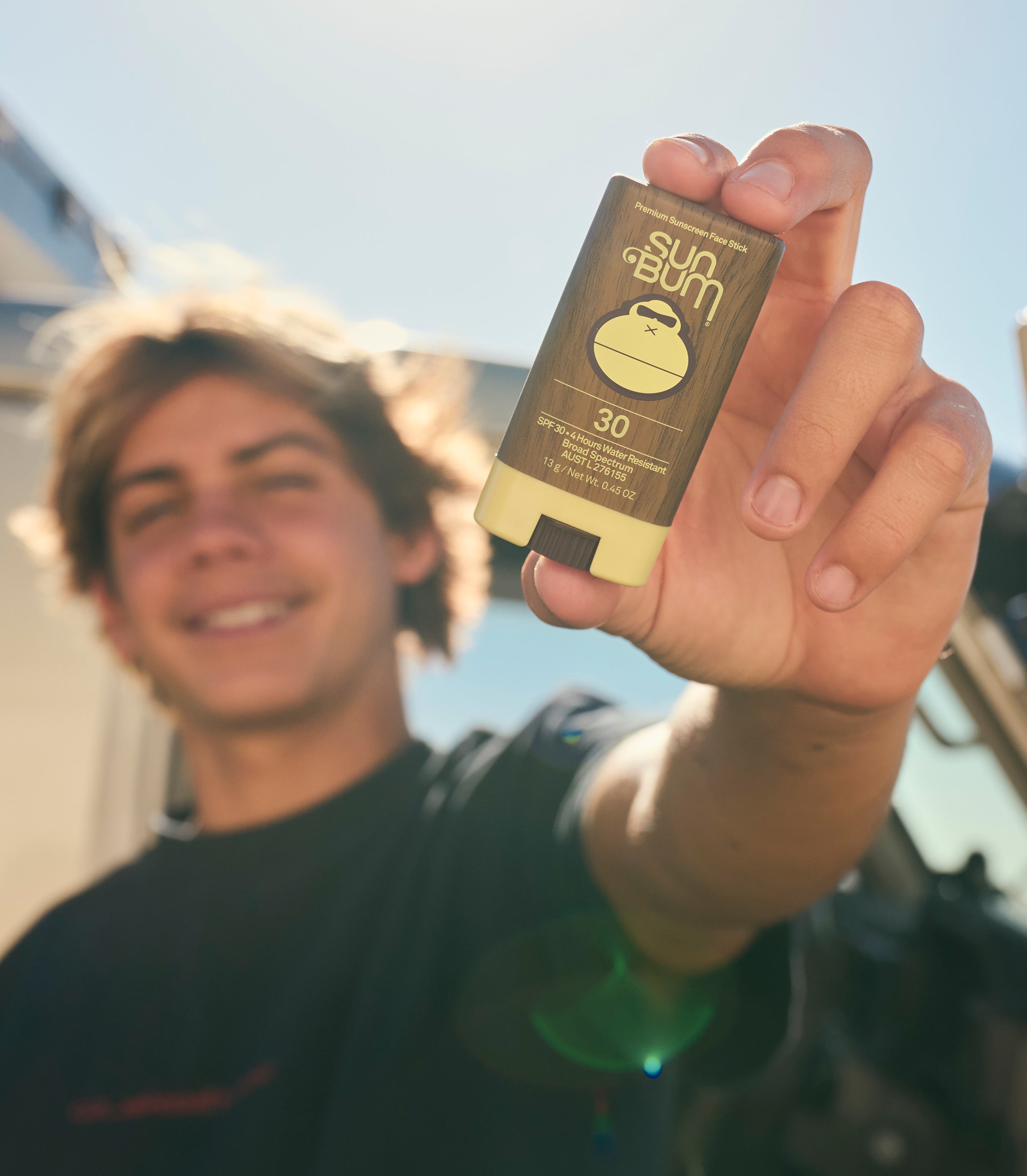 Person holding a sunscreen stick with a blurred background