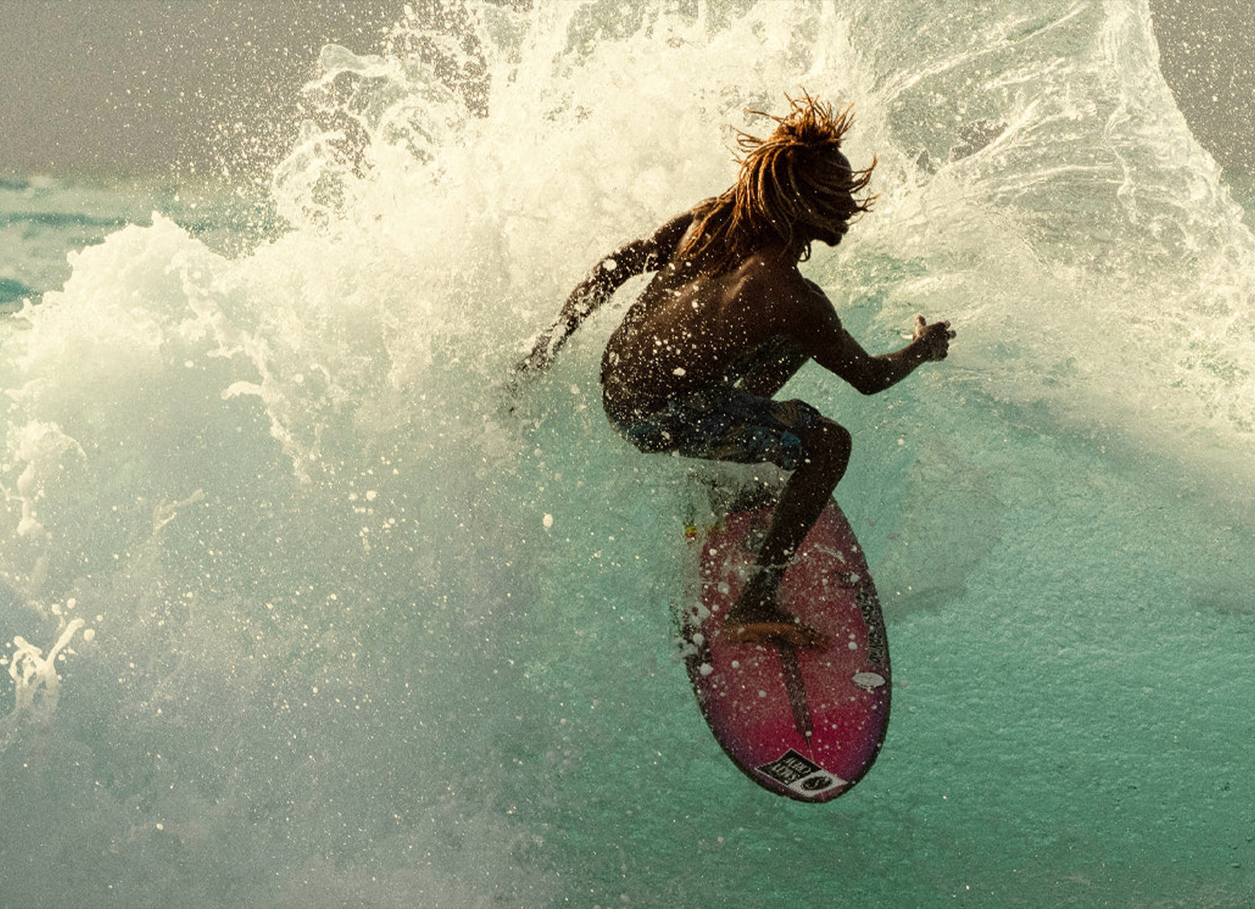 Person surfing on a wave with a pink surfboard