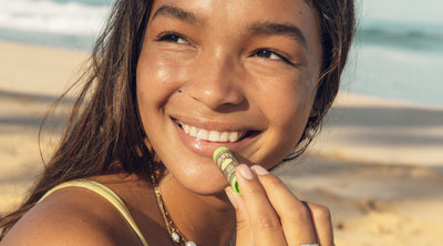 Woman eating a snack on a beach with ocean in the background